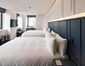 Family room with two king beds, TV screen, work desk and lounge seating at Page8, Page Hotels.