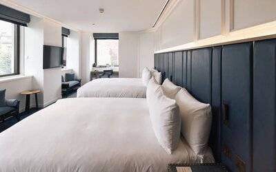 Family room with two king beds, TV screen, work desk and lounge seating at Page8, Page Hotels.