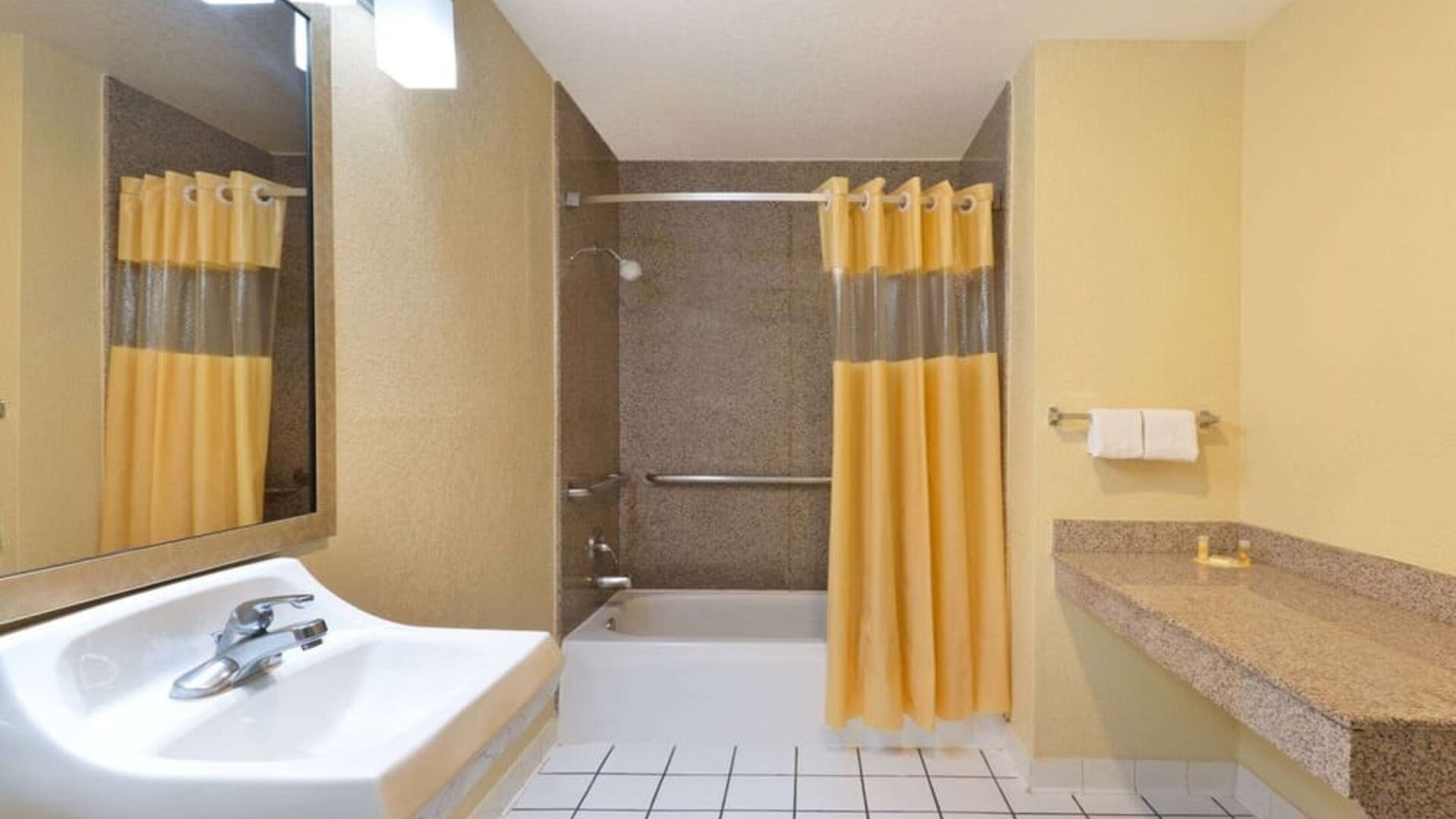 Guest bathroom with shower and tub at Days Inn By Wyndham San Antonio Northwest/Seaworld.