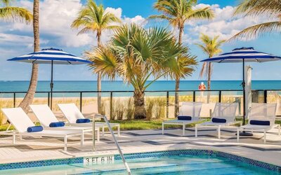 Refreshing outdoor pool surrounded by sun loungers with a view of the ocean at Plunge Beach Resort.
