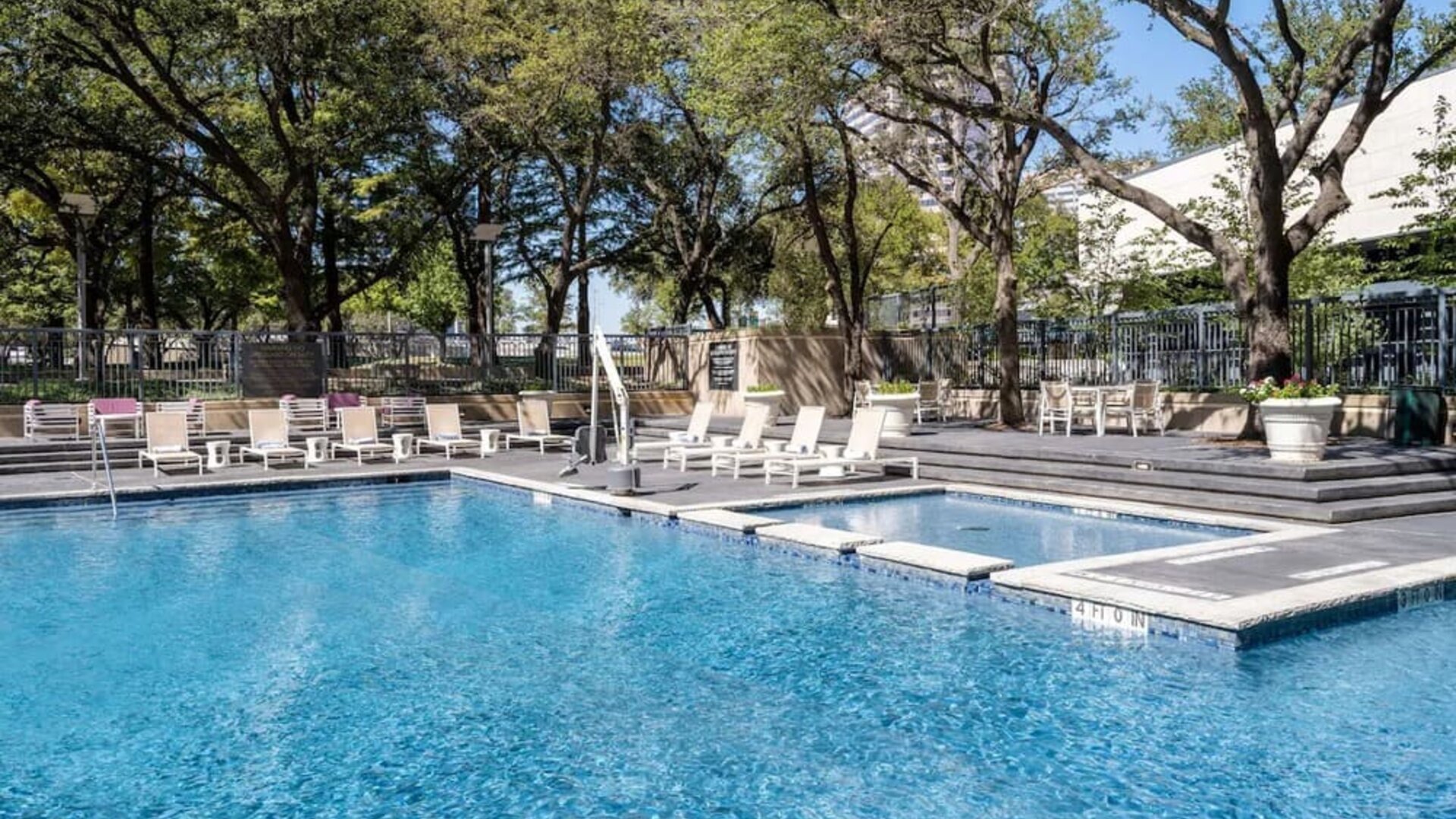 Refreshing outdoor pool surrounded by loungers at Hilton Dallas Lincoln Centre.