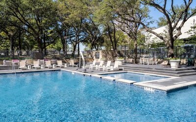 Refreshing outdoor pool surrounded by loungers at Hilton Dallas Lincoln Centre.