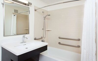 Private guest bathroom with combined shower and tub at Sonesta Simply Suites Dallas Las Colinas.