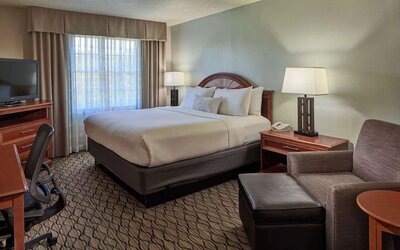 King bed with work desk and lounge seating at Sonesta Atlanta Airport South.