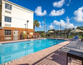 Outdoor pool with lounge chairs at Sonesta Simply Suites Miami Airport Doral.