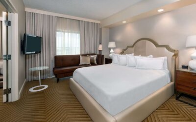 Comfortable king size bed with living area at Hilton Charlotte Airport.
