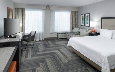 Spacious king bed room with work desk and sofa at Hampton Inn & Suites By Hilton Atlanta Perimeter Dunwoody.
