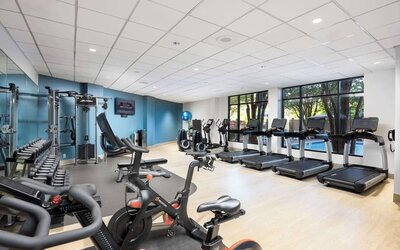 Well-equipped fitness center with a view of the pool at Doubletree By Hilton Houston Medical Center Hotel & Suites.