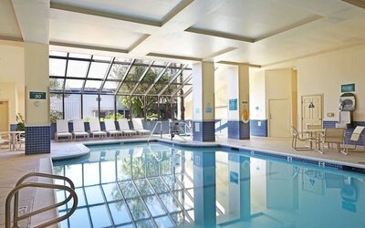 Relaxing indoor pool with lounge chairs at Embassy Suites By Hilton Los Angeles-Intl Airport North.