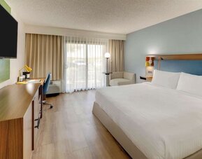 Day use room with king bed, work desk, sofa, TV screen and floor to ceiling window at Sonesta Select Scottsdale At Mayo Clinic Campus.