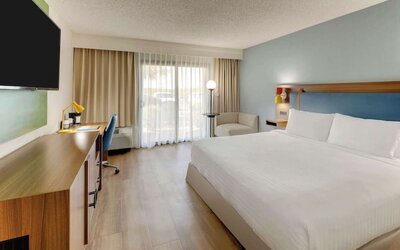 Day use room with king bed, work desk, sofa, TV screen and floor to ceiling window at Sonesta Select Scottsdale At Mayo Clinic Campus.