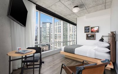 Delux king room with work desk and a view of the city at Moxy Boston Downtown.