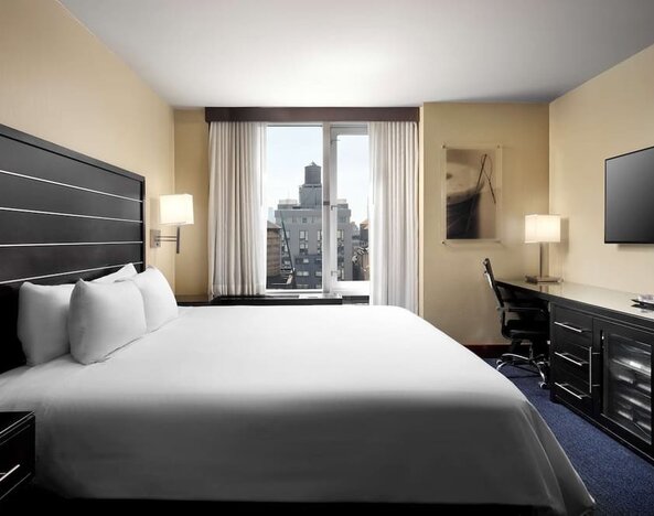 Delux king room with TV and work desk at Hilton New York Fashion District.