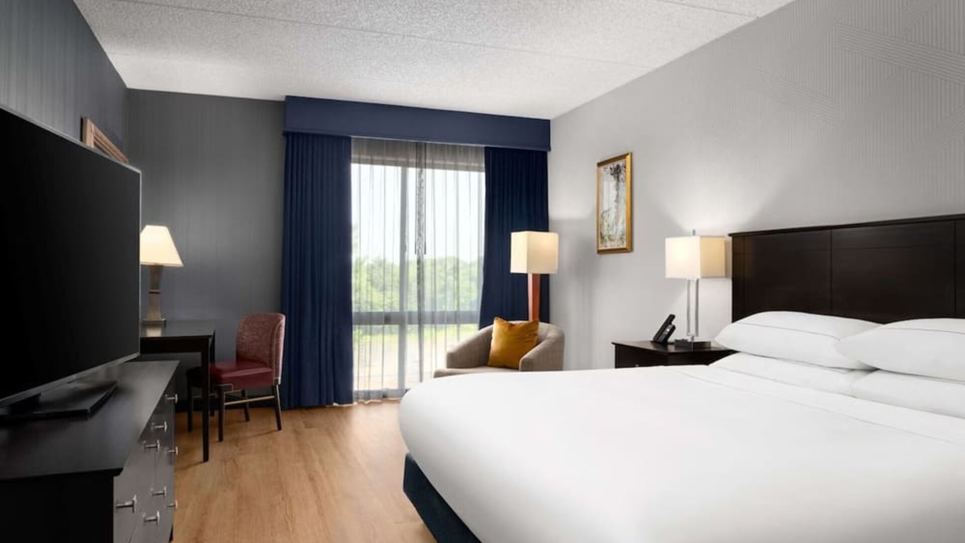 Day use room with floor to ceiling window, work desk, king bed and private bathroom at DoubleTree By Hilton Hartford - Bradley Airport.
