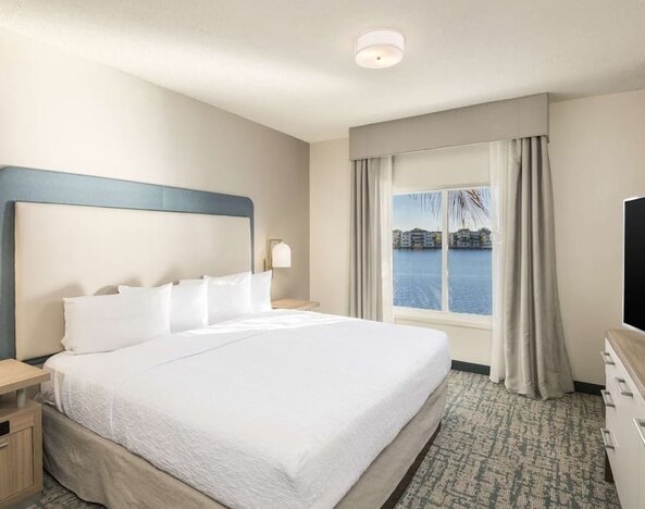 King bed with TV and a view of the Blue Lagoon at Homewood Suites By Hilton Miami Airport-Blue Lagoon.