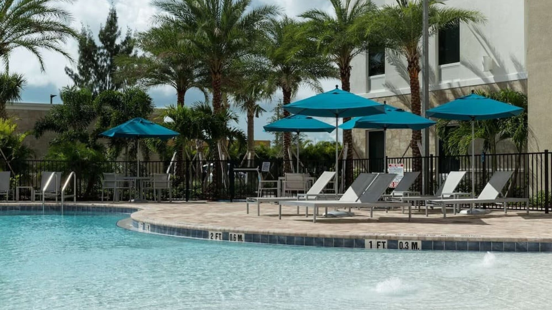 Outdoor pool with lounge chairs at Home2 Suites By Hilton Cape Canaveral Cruise Port.