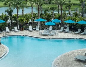 Outdoor pool with lounge seating at Home2 Suites By Hilton Cape Canaveral Cruise Port.