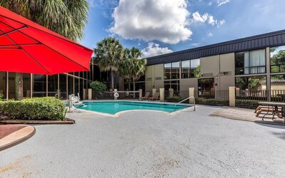 Hotel patio with lounge chairs and outdoor pool at Red Roof PLUS+ & Suites Houston - IAH Airport SW.