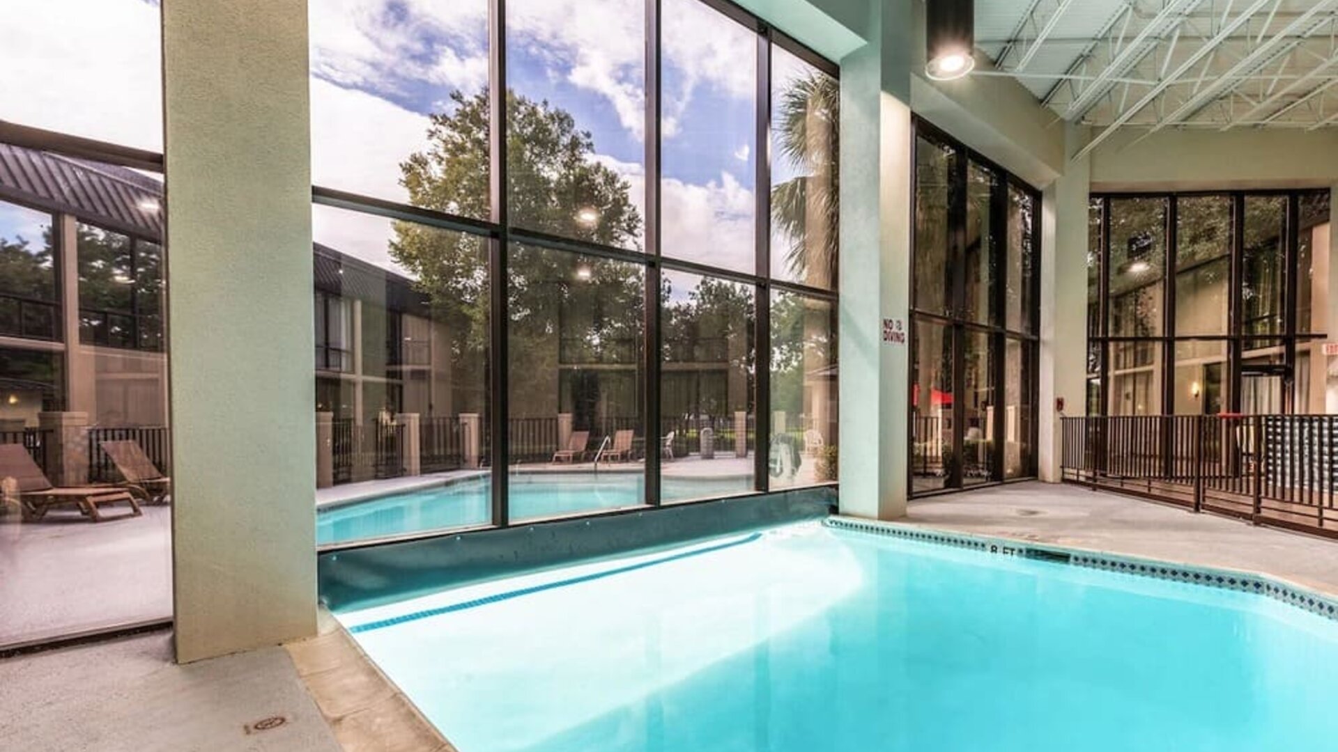 Combined indoor-outdoor pool with lounge seating at Red Roof PLUS+ & Suites Houston - IAH Airport SW.