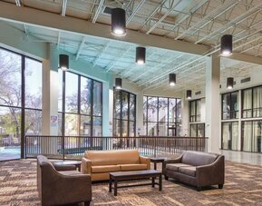 Comfortable lobby and coworking space with lots of natural light at Red Roof PLUS+ & Suites Houston - IAH Airport SW.