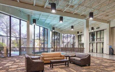 Comfortable lobby and coworking space with lots of natural light at Red Roof PLUS+ & Suites Houston - IAH Airport SW.