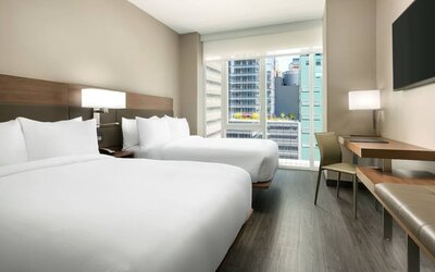 Day use twin room with workspace, floor to ceiling window and private bathroom at AC Hotel New York Times Square.