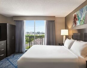 Day use room with king bed, balcony, TV screen and private bathroom at Embassy Suites By Hilton Miami - International Airport.