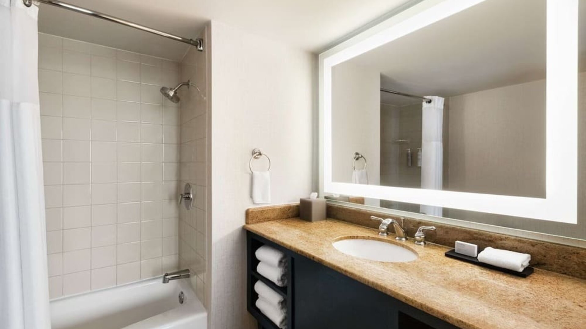 Private guest bathroom with combined shower and tub at Embassy Suites By Hilton Miami - International Airport.
