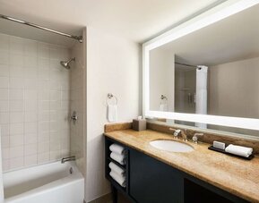 Private guest bathroom with combined shower and tub at Embassy Suites By Hilton Miami - International Airport.