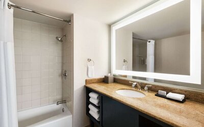 Private guest bathroom with combined shower and tub at Embassy Suites By Hilton Miami - International Airport.