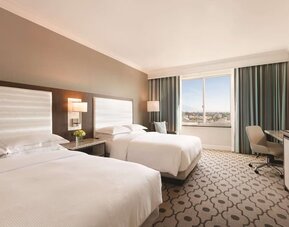 Comfortable day room with natural light, desk and chair at Hilton Los Angeles/San Gabriel for a relaxing daycation.