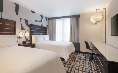 Guest room at the Hilton Fashion District, with a desk, chair and a view of the city.