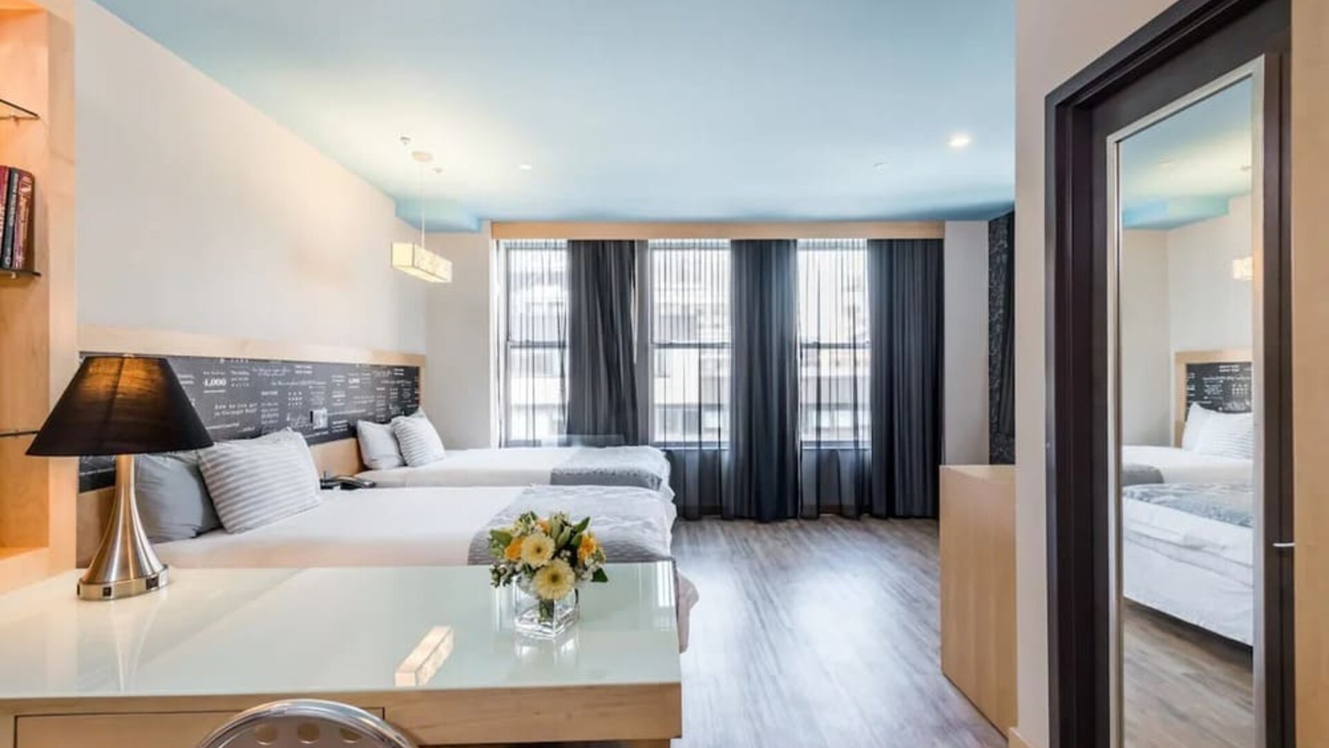 Room at the TRYP By Wyndham Times Square South containing desk, beds, and large windows.