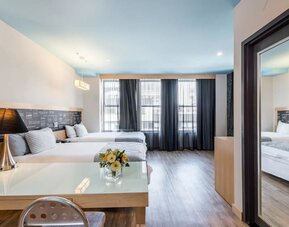 Room at the TRYP By Wyndham Times Square South containing desk, beds, and large windows.