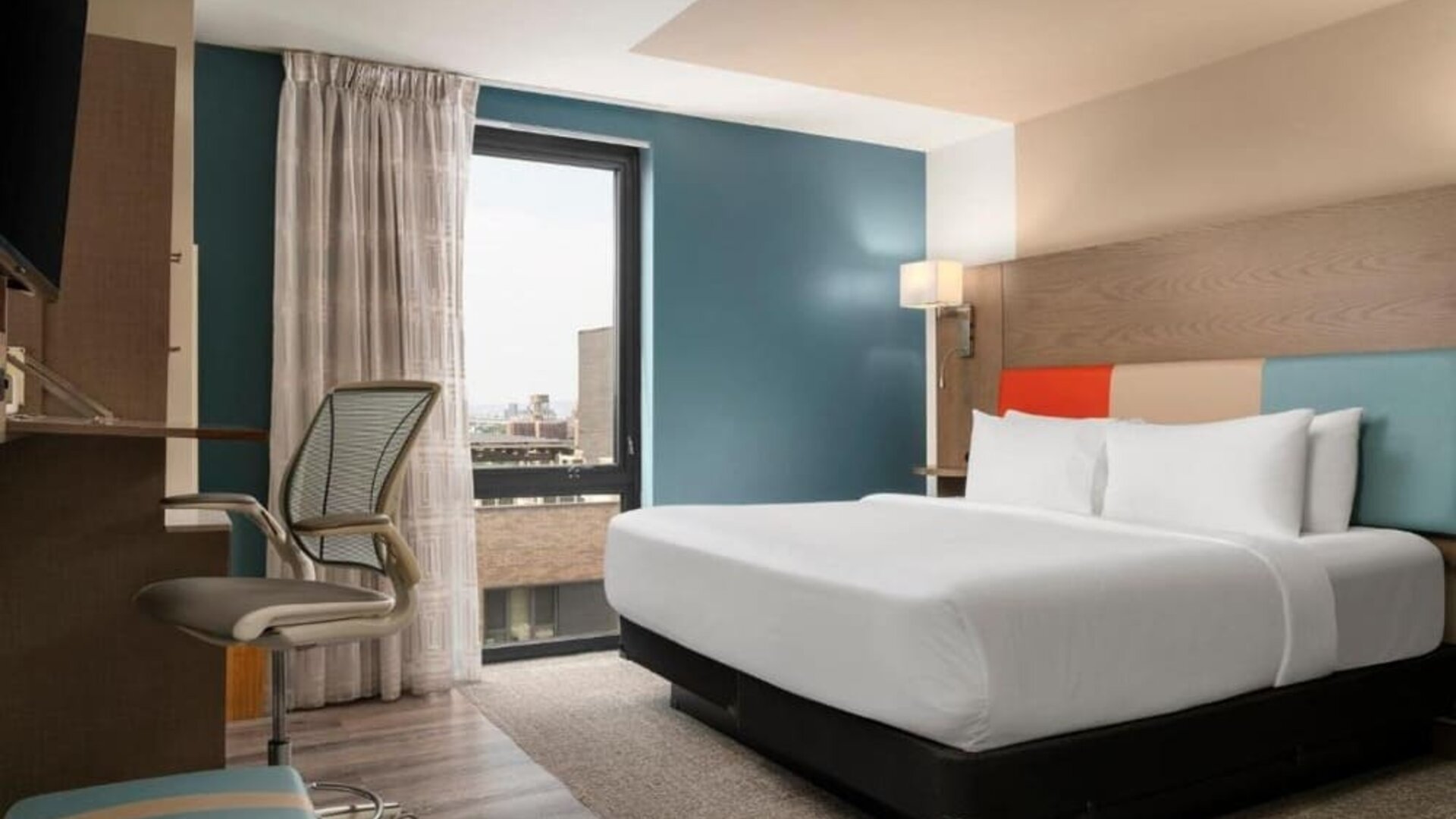 Day room featuring a desk and chair, with large windows offering beautiful city views at EVEN Hotel Brooklyn By IHG.