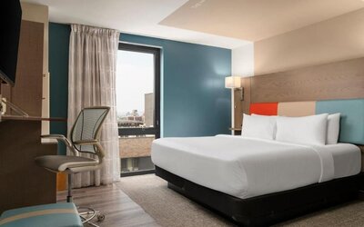 Day room featuring a desk and chair, with large windows offering beautiful city views at EVEN Hotel Brooklyn By IHG.