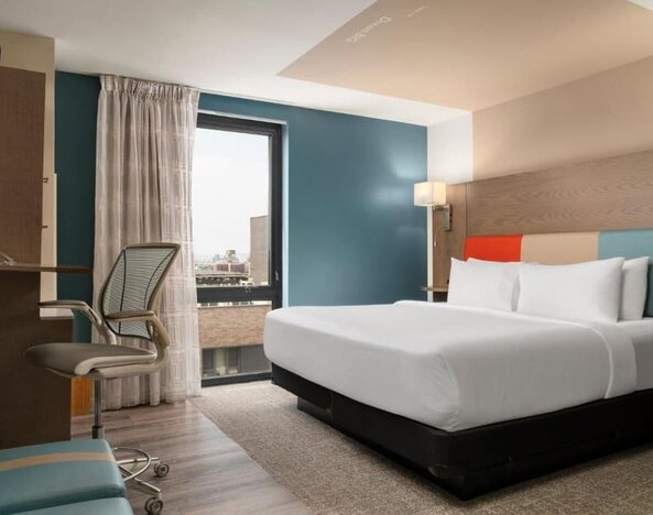 Day room featuring a desk and chair, with large windows offering beautiful city views at EVEN Hotel Brooklyn By IHG.