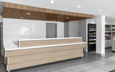Reception area at Hilton Garden Inn Queens/JFK Airport with wood desk, and a white counter.