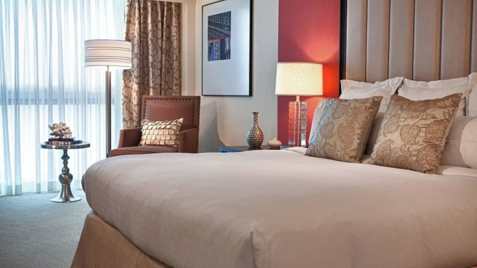 Guest room with king bed, accent pillows, armchair, floor lamp, and window seating area at Renaissance Newark Airport Hotel.