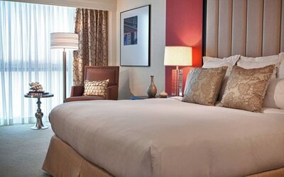 Guest room with king bed, accent pillows, armchair, floor lamp, and window seating area at Renaissance Newark Airport Hotel.
