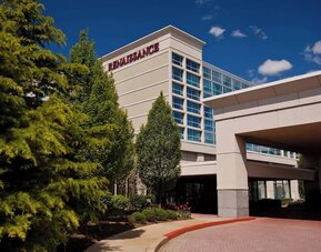 Hotel exterior with Renaissance signage, entrance canopy, trees, and driveway at Renaissance Newark Airport Hotel.