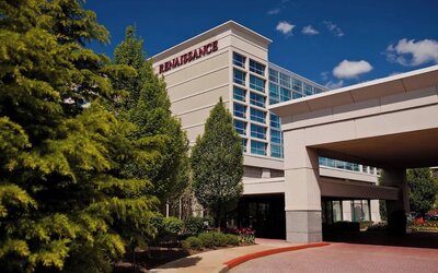 Hotel exterior with Renaissance signage, entrance canopy, trees, and driveway at Renaissance Newark Airport Hotel.