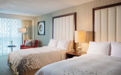 Guest room with two double beds, bedside lamp, armchair, and sheer curtains at Renaissance Newark Airport Hotel.