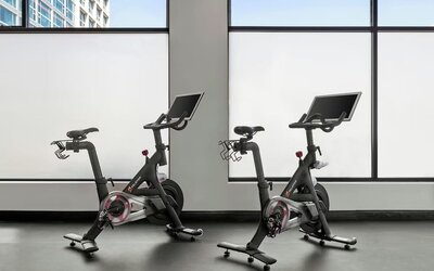 Two stationary bikes facing large windows in fitness area at Renaissance Newark Airport Hotel with city view.