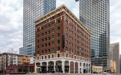 Exterior of multi-story brick building on city corner with surrounding towers at Kimpton Palladian Hotel.