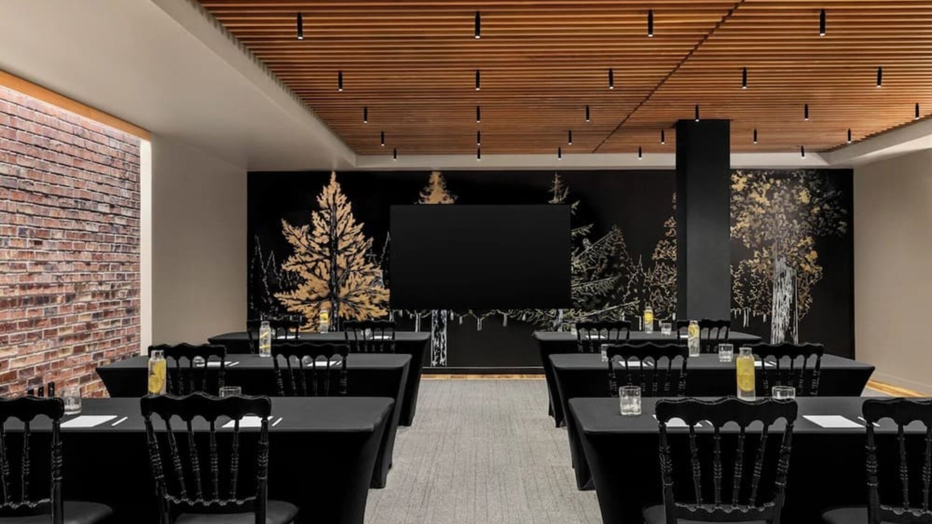 Meeting room with rows of tables, black tablecloths, chairs, and mural wall at Kimpton Palladian Hotel.