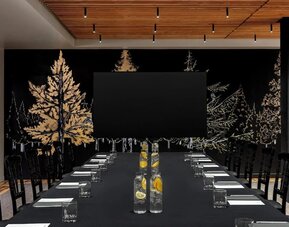 Conference setup with long table, water bottles, notepads, and large screen at Kimpton Palladian Hotel.