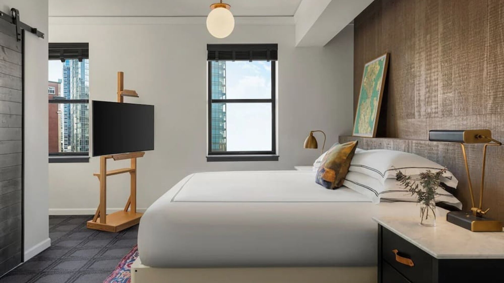 Bedroom with king bed, wood accent wall, desk, and city view window at Kimpton Palladian Hotel.