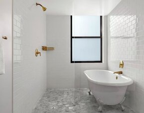 Bathroom with freestanding clawfoot tub, white tile walls, and brass fixtures at Kimpton Palladian HotelTwin bedroom with two beds, framed artwork, wall-mounted TV, and natural light at Kimpton Palladian Hotel.
