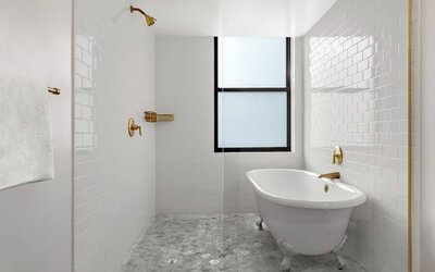 Bathroom with freestanding clawfoot tub, white tile walls, and brass fixtures at Kimpton Palladian HotelTwin bedroom with two beds, framed artwork, wall-mounted TV, and natural light at Kimpton Palladian Hotel.